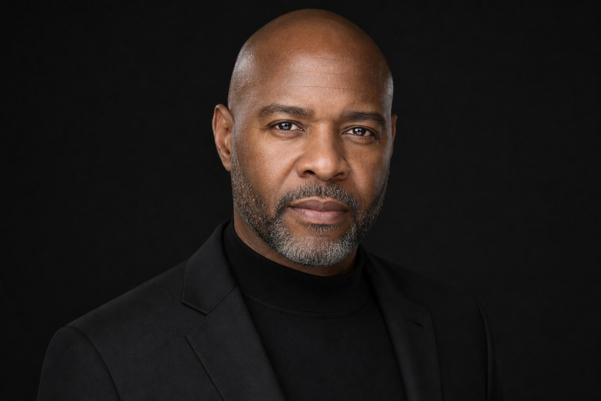 Professional studio headshot in a black turtleneck against a dark background.